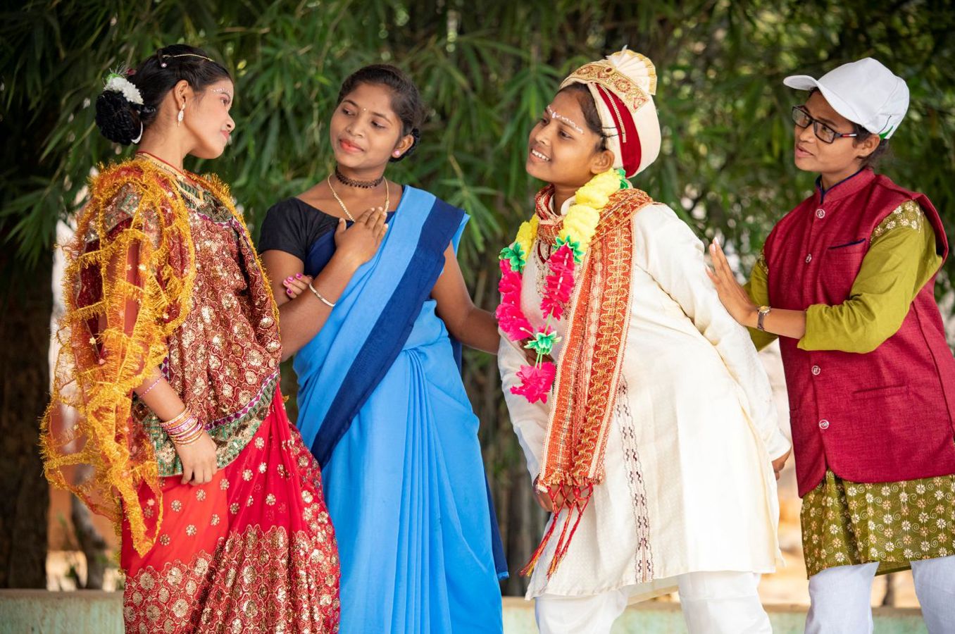 A group of four girls dressed in different costumes perform a play on a stage.